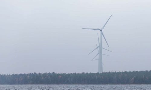 Vindkraftverk i dimma vid vattnet